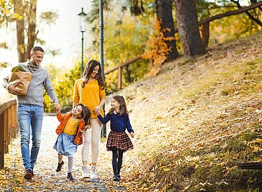 Husband and wife walk in the forest with their two daughters